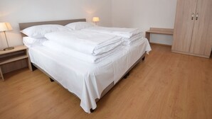 Un lit bien fait, avec du linge de lit blanc, deux tables de chevet avec des lampes et une armoire en bois.