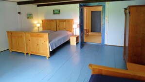 Une chambre à coucher avec un lit en bois, une table de chevet, une lampe et une porte qui donne sur une autre pièce.