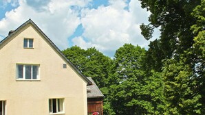 Une maison à deux étages avec un toit en pente, une clôture en bois et une pelouse.