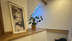 Una escalera con un cuadro enmarco, una planta en maceta y una silla.