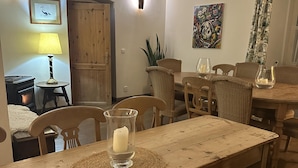 Un comedor con mesa de madera, sillas, una vela y un cuadro en la pared.