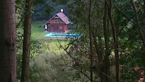 Un chalet rustique avec un toit en pente, entouré d’une forêt dense.