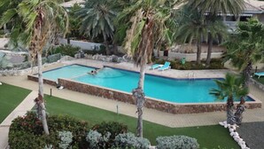 A swimming pool surrounded by palm trees and well-maintained landscaping. - Sea-view Apartment in Mambo Beach Near Seaaquarium (Willemstad)