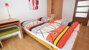 Un dormitorio con una cama de madera, un escritorio con una lámpara, un armario y una puerta.