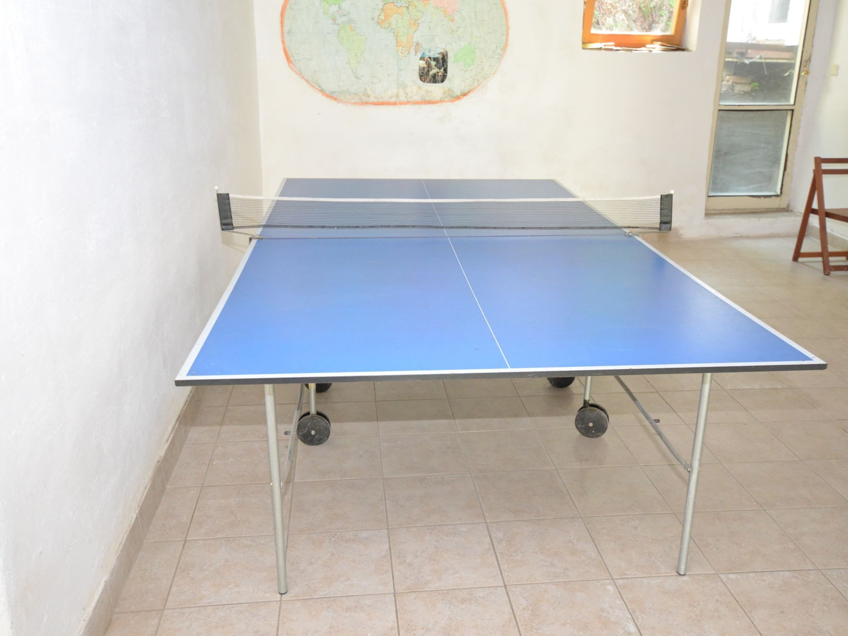 A ping pong table in a room with tiled flooring and a map on the wall.