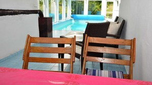 A room with a pool view, wooden chairs, a table, and a wicker sofa. - South Bohemia Family Escape (Bechyne)