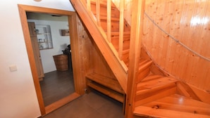 A wooden staircase leading to a second floor, with a kitchen area visible in the background. - Holiday Home in Forest With Private Pool (Petrohrad)