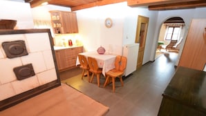 A kitchen with wooden cabinets, a dining table with chairs, a refrigerator, and a clock on the wall. - Holiday Home in Forest With Private Pool (Petrohrad)