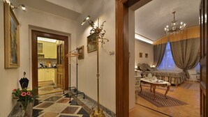 A hotel room with a wooden floor, a chandelier, a dining area with a table and chairs, and a view of the kitchen through an open door. - Charming Prague Downtown Flat (Prague)