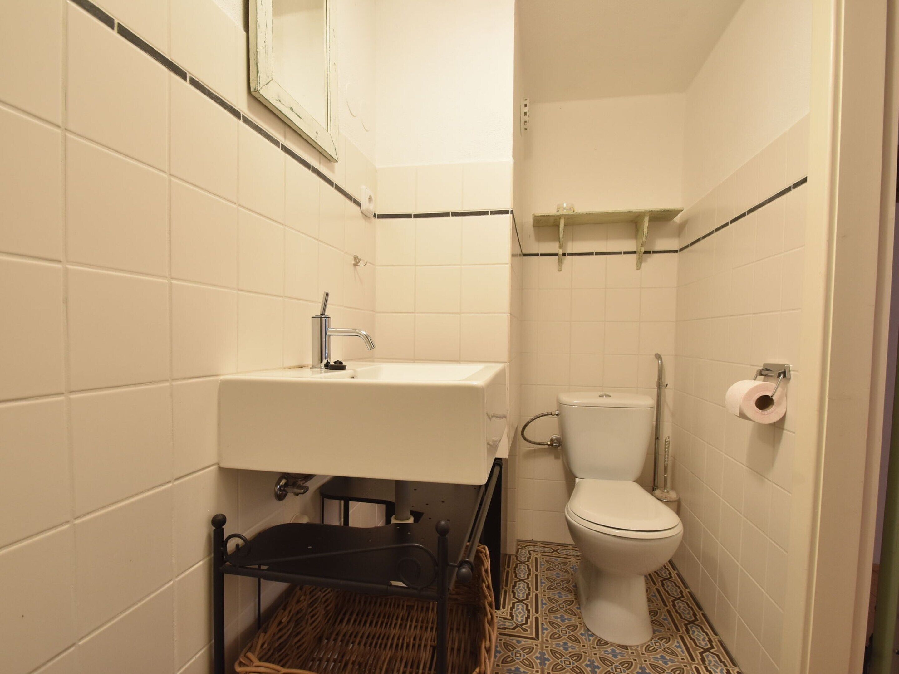 A small bathroom with a white sink, a toilet, and a shower area.