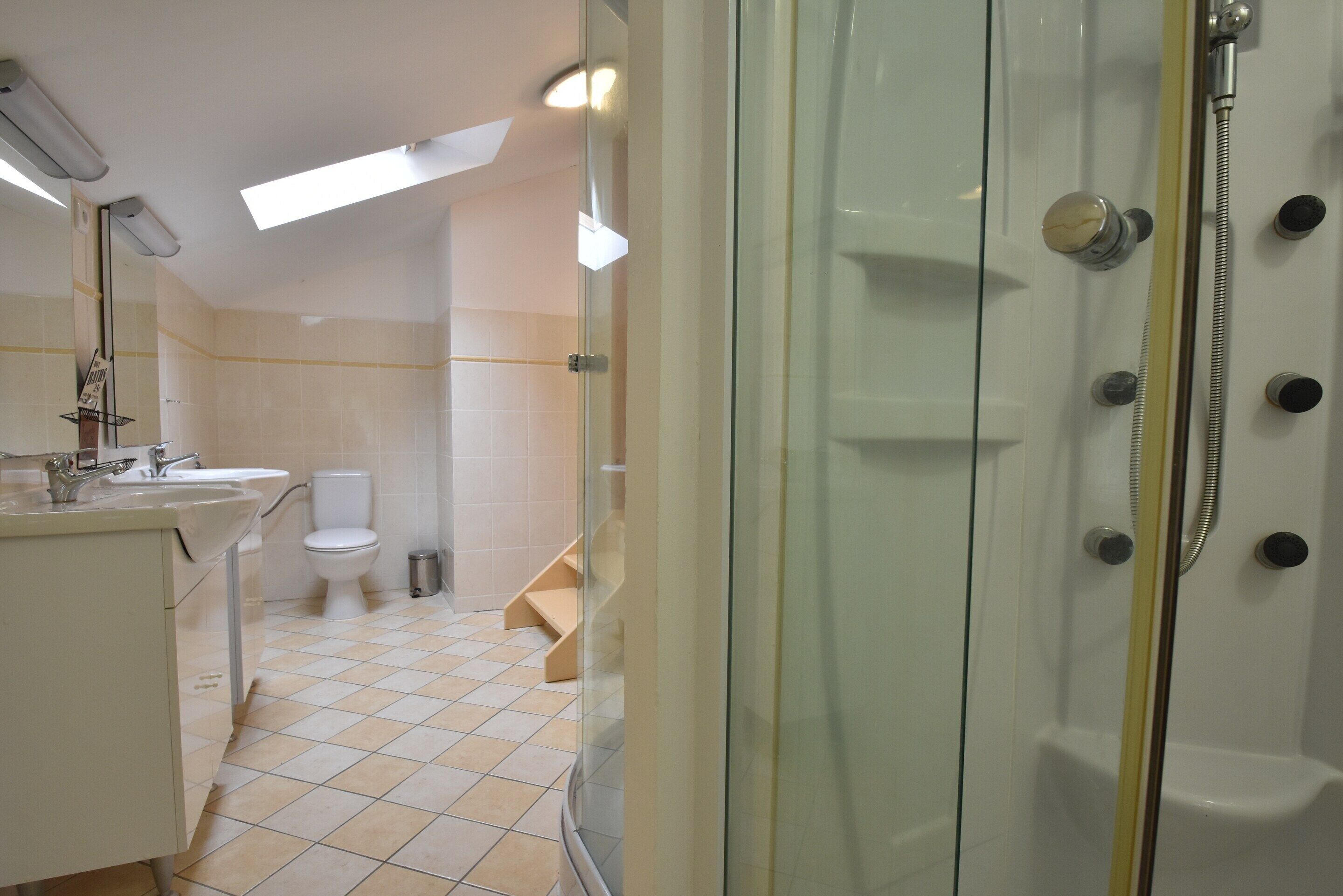 A modern bathroom with a glass shower enclosure, a toilet, and a sink.