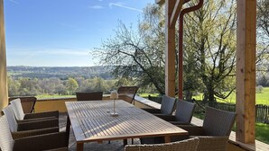 Eine Terrassensitzgruppe im Freien mit Holztisch und Korbstühlen mit Blick auf eine malerische Landschaft.