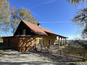 A house with a sloped roof, wooden exterior, and a fenced yard.