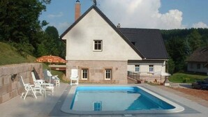 Een huis met zwembad, stenen gevel en een klein raam.