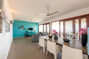 A spacious living area with a dining table, chairs, a sofa, and a TV. - Luxurious Apartment in Jan Thiel With Pool (Jan Thiel)