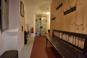 A hallway with a wooden bench, a fire extinguisher, and a door with a sign.