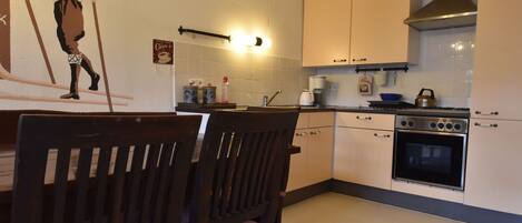 A kitchen with wooden chairs, a stove, and a coffee machine.
