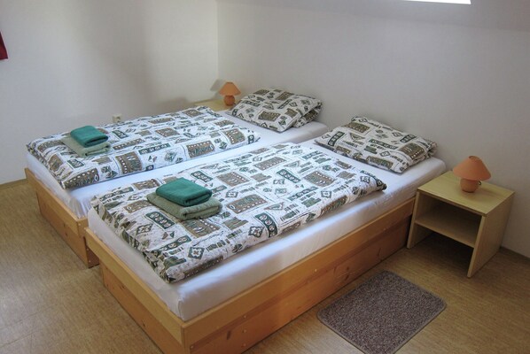 A double bed with patterned bedding, two bedside tables with lamps, and a small rug on a wooden floor.