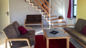 A living room with a wooden staircase, two sofas, a coffee table, and a red rug.