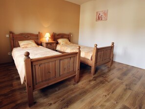 Una habitación con dos camas de madera, una mesita de noche con lámpara y un cuadro en la pared.