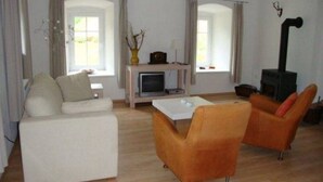 Un salon comprenant un canapé, deux fauteuils, une table basse, une cheminée et un téléviseur.