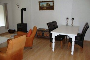 A living room with a white table, black chairs, a sofa, a fireplace, and a painting on the wall. - Holiday Home in Vidochov Near Ski Slopes (Vidochov)
