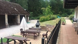 Une terrasse extérieure avec des tables de pique-nique et un barbecue.