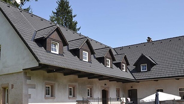 Un bâtiment doté de plusieurs toits à pignon et de fondations en pierre.
