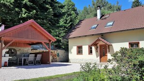 A rustic cabin with a wooden porch, a stone wall, and a gravel driveway. - Elite Cottage in Turnov near Ski Area (Turnov)