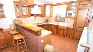 A kitchen with wooden cabinets, a brick island, a sink, a microwave, and a window with a view. - Elite Cottage in Turnov near Ski Area (Turnov)