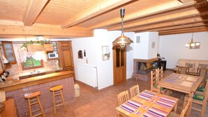 A rustic kitchen with wooden cabinets, a brick backsplash, and a wooden dining table with striped placemats. - Elite Cottage in Turnov near Ski Area (Turnov)
