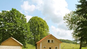A rural house with a stone extension, surrounded by lush greenery and a clear sky. - Holiday Home Milire Bohemian Forest (Milire)