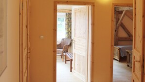 A hallway with wooden doors leading to a room with a bed and a chair. - Holiday Home Milire Bohemian Forest (Milire)