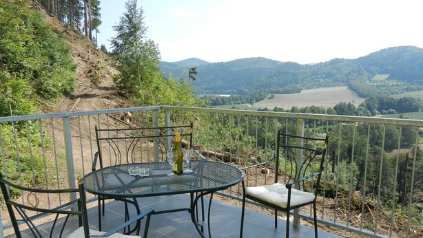 A terrace with a round table and four chairs, overlooking a scenic valley with hills and trees. - Comfortable Villa in Nedvedice With Private Garden (Nedvedice)