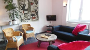 A living room with two wicker chairs, a black sofa, a coffee table with a chessboard, a TV, and a large abstract painting on the wall. - Comfortable Villa in Nedvedice With Private Garden (Nedvedice)