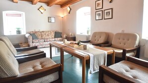 Un salon chaleureux avec des poutres en bois, un canapé à motifs floraux, deux fauteuils et une table basse.
