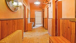 A hallway with wooden paneling, a bench, a radiator, a mirror with lights, and antler decorations. - Mountain Home With Garden (Cerny Dul)