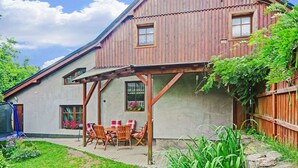 A wooden house with a covered patio area, a stone wall, and a garden with various plants. - Mountain Home With Garden (Cerny Dul)