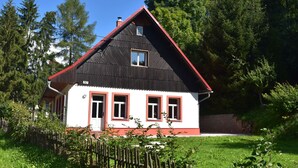A two-story house with a red roof and white walls, surrounded by a wooden fence and greenery. - Holiday Home Rudnik Near Ski Lift (Rudník)