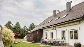 A house with a patio, outdoor seating, and a garden.
