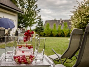 A patio table with a pitcher of water, glasses, and a bowl of berries.
