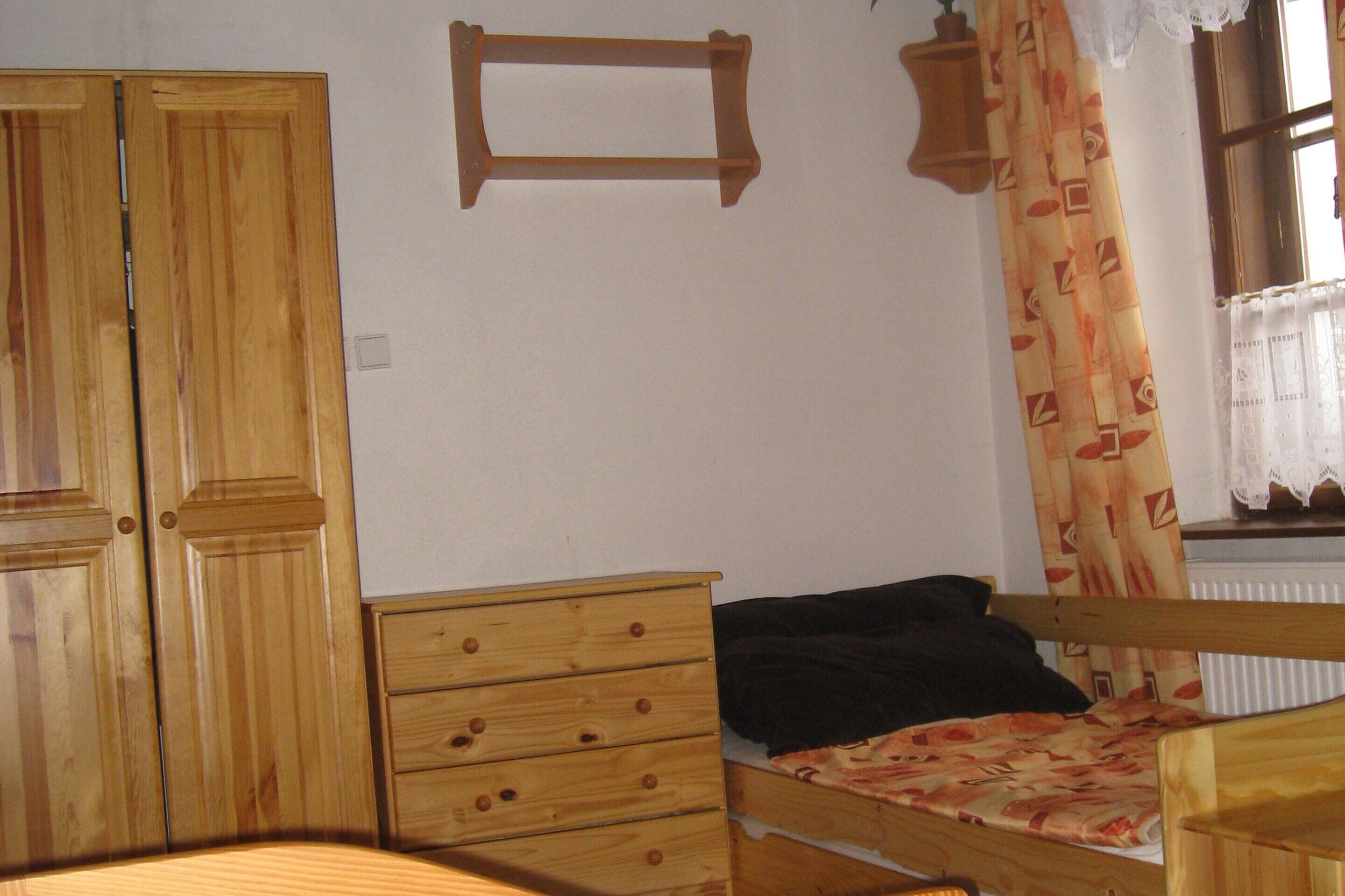 A bedroom with a wooden bed, a wooden dresser, and a wooden wardrobe.