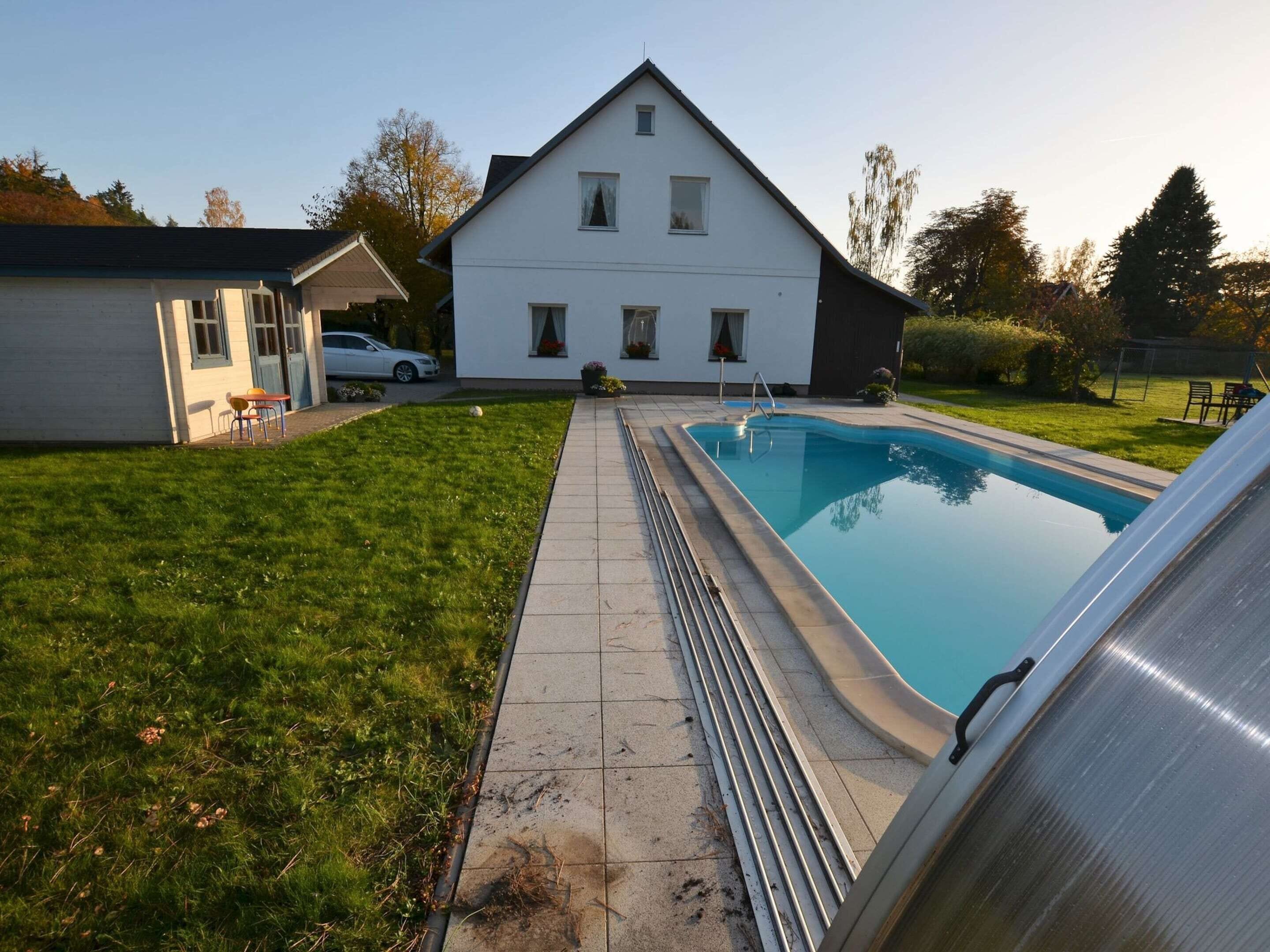 A residential property with a swimming pool, a covered patio, and a two-story house.