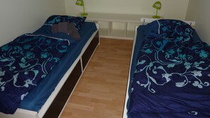 A room with two single beds, each with a blue floral bedspread and a green desk lamp. - Cozy Holiday Home in Rostock Germany near Beach (Rostock)