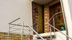 A staircase with metal railings leading to a brick entrance with a wooden door and a potted plant. - Restful Apartment in Neukloster Germany near Lake (Neukloster)