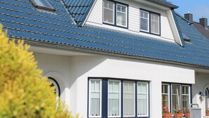 A house with a blue tiled roof, white walls, and multiple windows. - Wohnung mit Balkon in Zingst Deutschland (Zingst)
