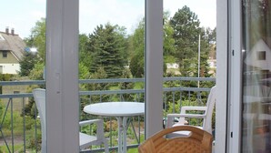 A balcony with a white table and chairs, a wicker chair, and a metal railing. - Wohnung mit Balkon in Zingst Deutschland (Zingst)