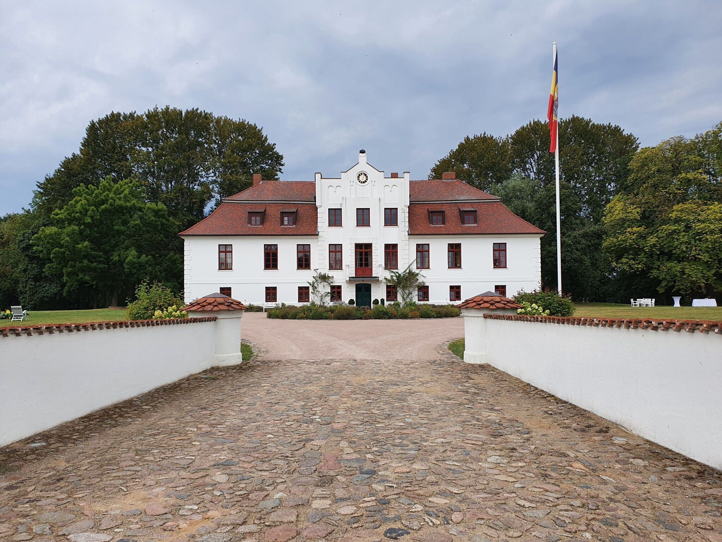 A large white building with a symmetrical facade, a central entrance, and a flagpole.