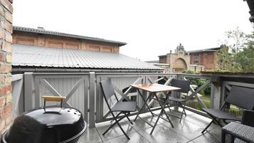 Eine Außenpatio-Terrasse mit Grill, Klappstühlen und einem Tisch.