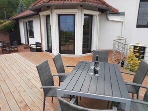 A covered patio with a table and chairs, a bottle of wine, and a glass. - Gruppenunterkunft mit Pool in Ballenstedt (Ballenstedt)